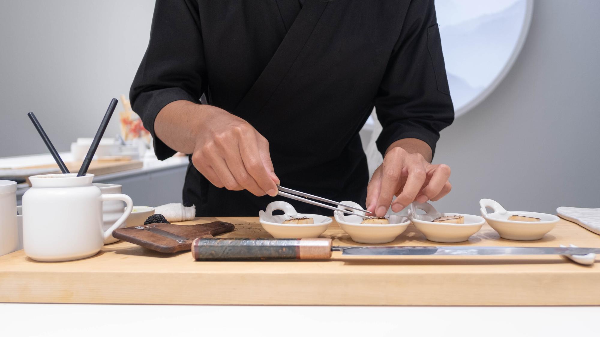 Instructor plating a composed entrée in workshop
